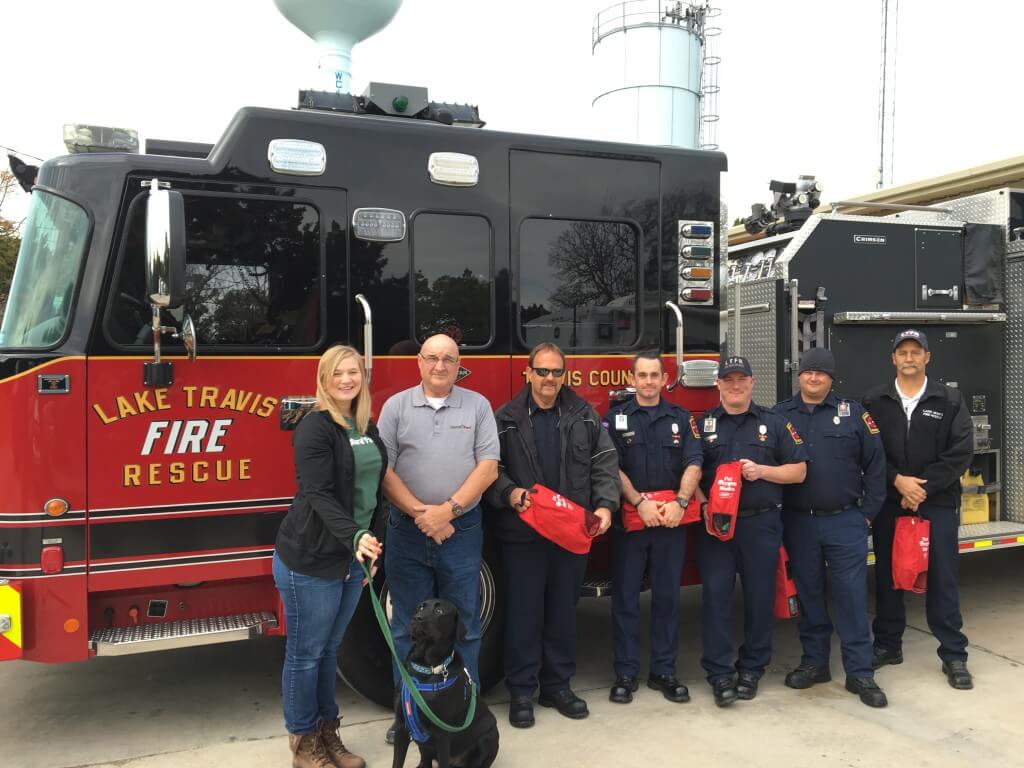 Lake Travis Fire Rescue firefighters receive a gift of oxygen masks from Natural Pawz, a new pet food and supplies store opening Jan. 9 in Steiner Ranch. Kelly Green, show at the left with her dog Buddy, will manage the store. Co-founder, Biff Picone, second from the left, was also at the LTFR donation event last week.    